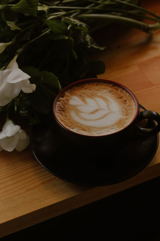 Une tasse de café avec des fleurs blanches sur une table en bois